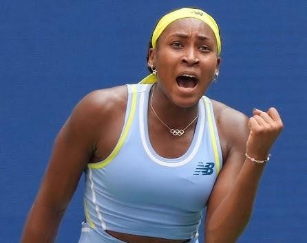 Coco Gauff w zbliżeniu na korcie tenisowym, podczas serwisu lub uderzenia forehand, z intensywnym wyrazem skupienia na twarzy.