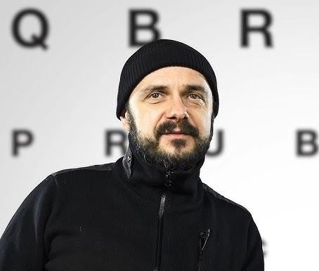Alt: Zbliżenie na twarz Arkadiusza Jakubika, ukazujące ekspresję i skupienie, z dramatycznym oświetleniem podkreślającym rysy aktora.