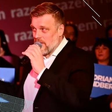 Adrian Zandberg podczas publicznego wystąpienia lub debaty, aktywnie angażujący się w dyskusję.