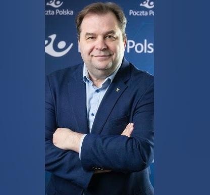 Dynamiczny portret Sebastiana Mikosza w garniturze, z rozmytym tłem łączącym pas startowy lotniska i nowoczesną placówkę Poczty Polskiej, symbolizujący jego kluczowe osiągnięcia w karierze menedżerskiej.