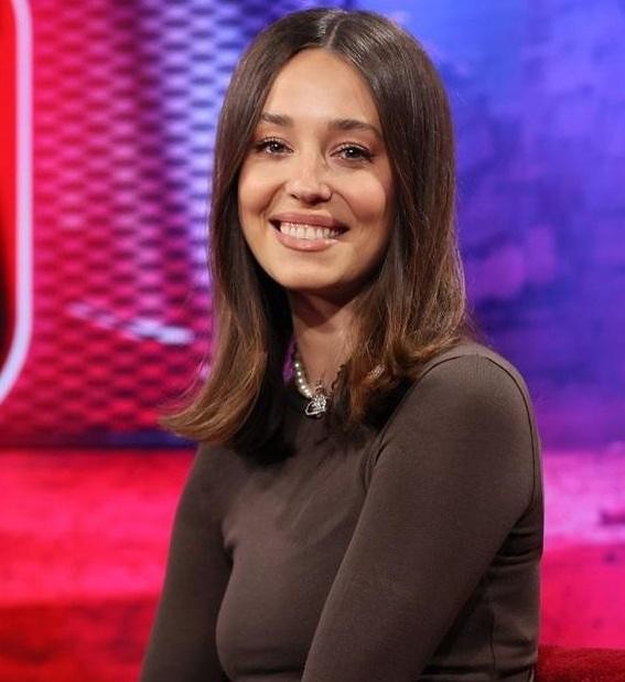 Izabella Krzan na planie programu telewizyjnego, dynamicznie prowadząca audycję, z uśmiechem na twarzy.