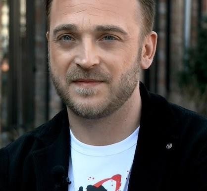 Mateusz Gessler w akcji, gotujący lub prezentujący danie w profesjonalnej kuchni restauracyjnej.