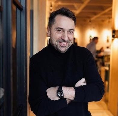 Marcin Miller uśmiechający się i patrzący prosto w obiektyw, ukazujący jego optymistyczną i przystępną naturę.