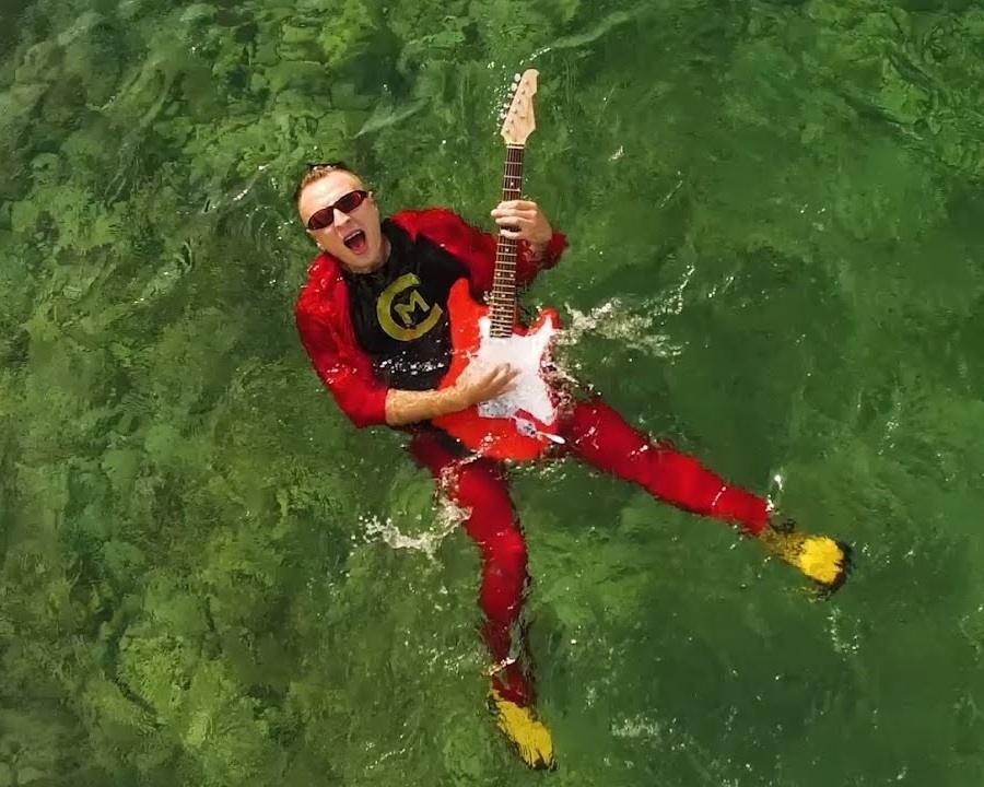 Czadoman podczas energicznego występu na żywo, z kolorowymi światłami scenicznymi i widownią w tle, ukazujący jego charyzmę.