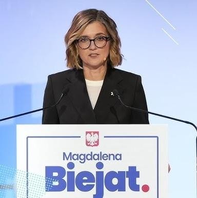 Magdalena Biejat podczas przemówienia publicznego, z dynamicznym gestem, symbolizującym jej zaangażowanie i pasję polityczną.